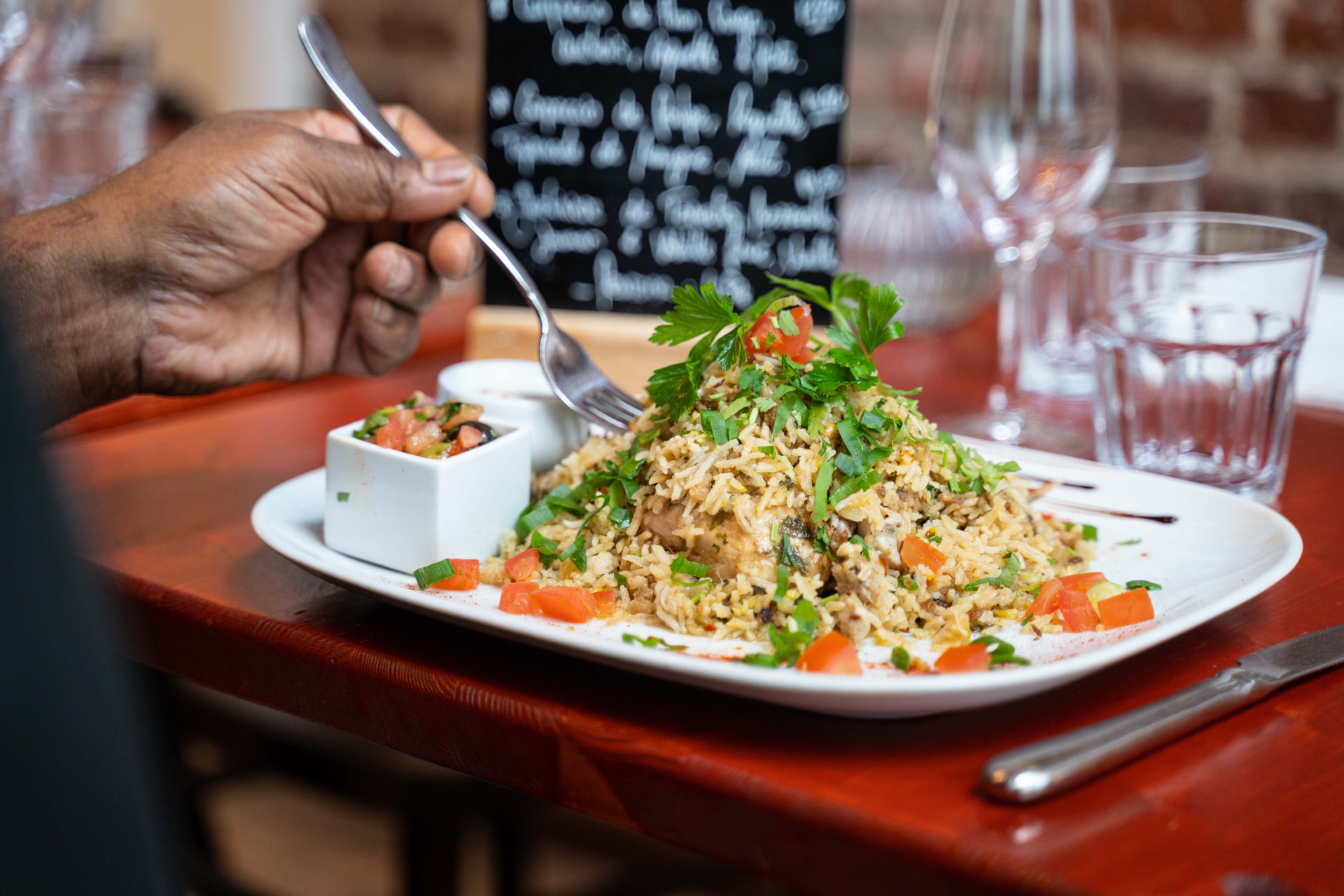 Biryani servi à table dans la salle aux murs de briques des Marmites du Monde