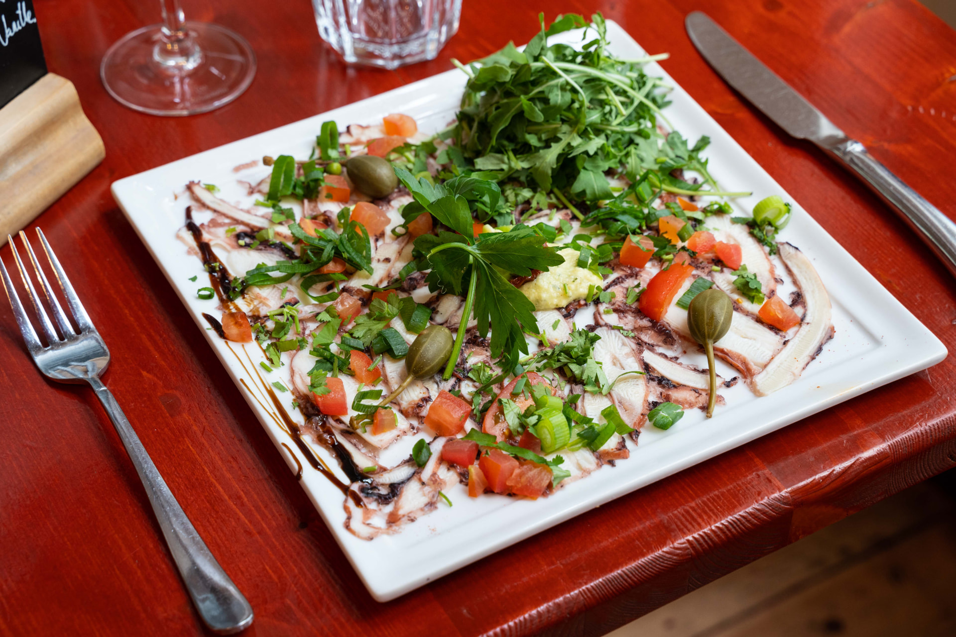 Carpaccio de poulpe grillé, roquette, câpres et tomates fraîches